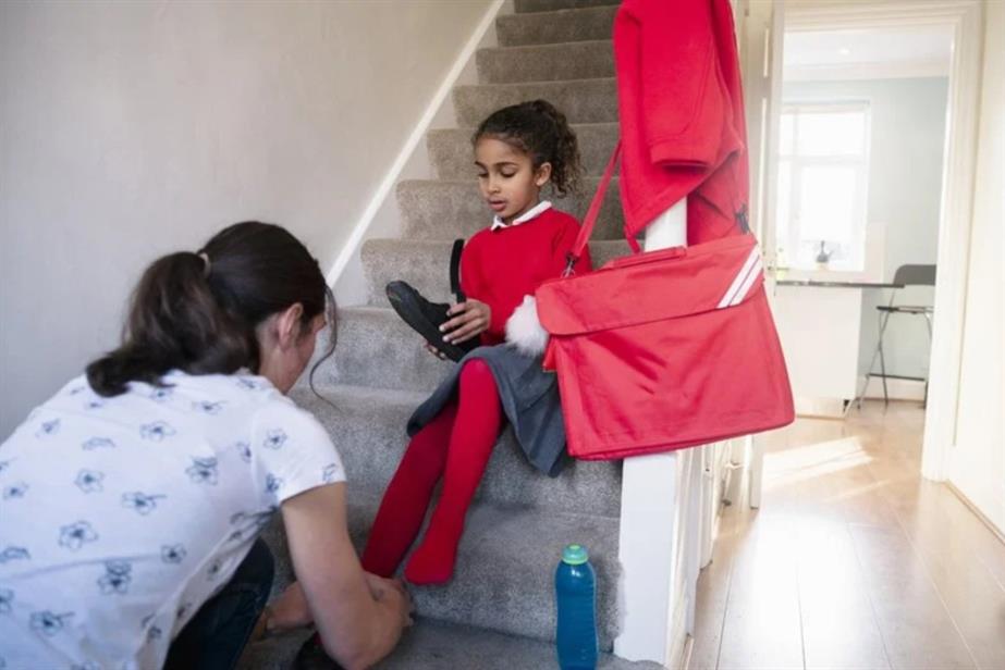 Woman helping girl put on shoes