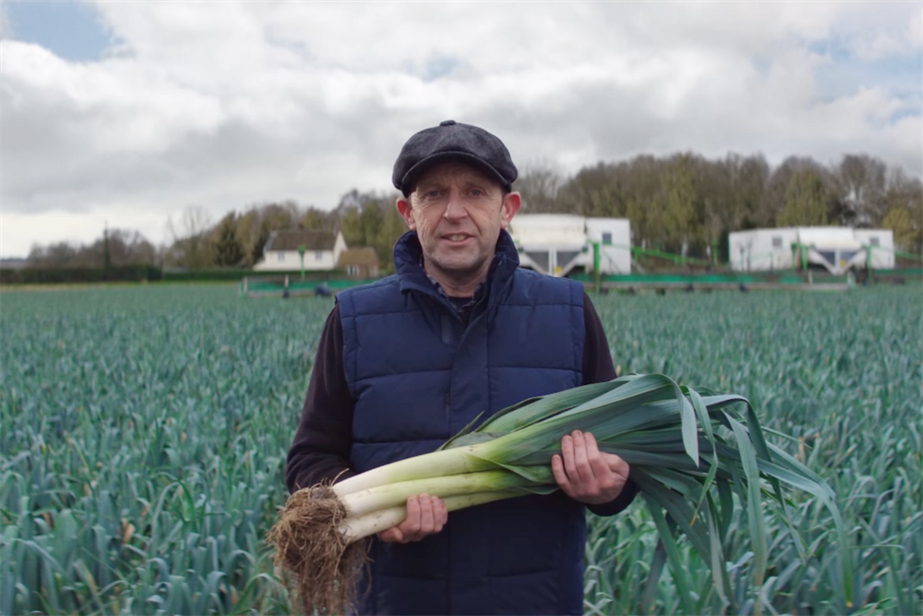 A farmer holds leeks in a field